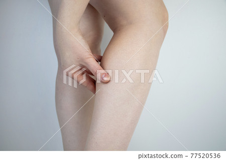 A woman suffers from pain in the calves. Stretching the calf muscle, varicose veins, leg cramps, or myositis. Orthopedic doctor examines patient 77520536