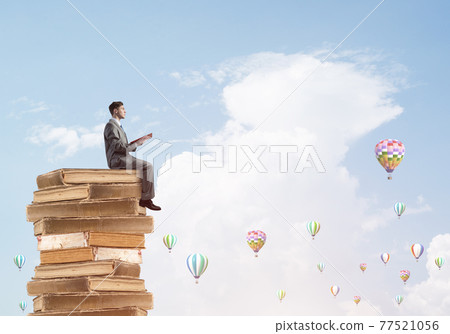 Man student reading book and aerostats flying around in air Man student reading book and aerostats flying around in air 77521056