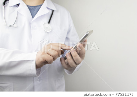 The doctor is holding a smartphone. Medical consultation by phone. Mobile app for healthcare providers The doctor is holding a smartphone. Medical consultation by phone. Mobile app for healthcare providers 77521175