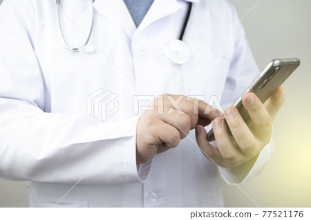 The doctor is holding a smartphone. Medical consultation by phone. Mobile app for healthcare providers The doctor is holding a smartphone. Medical consultation by phone. Mobile app for healthcare providers 77521176