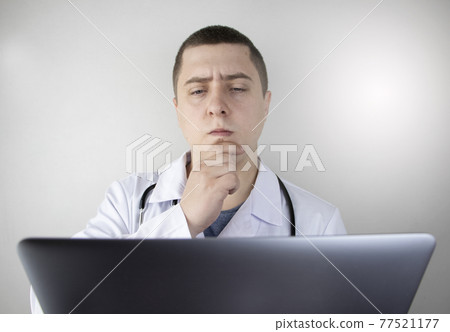 Workplace of a doctor. Male therapist works at a computer. The concept of modern medicine and technology used by medical professionals Workplace of a doctor. Male therapist works at a computer. The concept of modern medicine and technology used by medical professionals 77521177