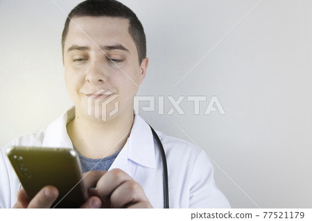 The doctor is holding a smartphone. Medical consultation by phone. Mobile app for healthcare providers The doctor is holding a smartphone. Medical consultation by phone. Mobile app for healthcare providers 77521179