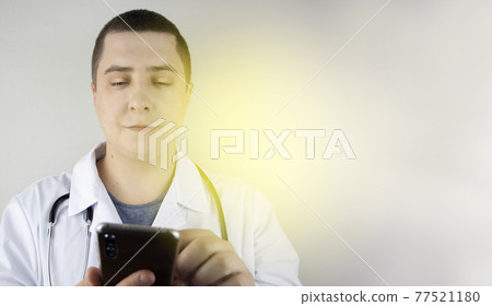 The doctor is holding a smartphone. Medical consultation by phone. Mobile app for healthcare providers The doctor is holding a smartphone. Medical consultation by phone. Mobile app for healthcare providers 77521180