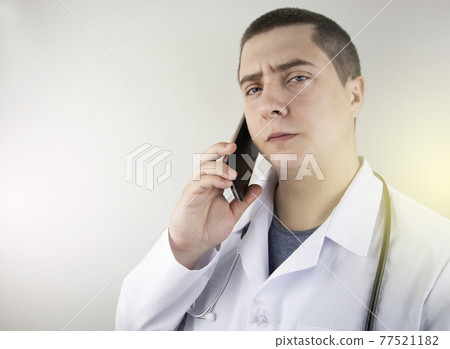 The doctor is talking on the phone with the patient. Remote assistance by phone. Modern medicine. The doctor answers questions on the mobile. The doctor is talking on the phone with the patient. Remote assistance by phone. Modern medicine. The doctor answers questions on the mobile. 77521182