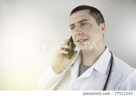 The doctor is talking on the phone with the patient. Remote assistance by phone. Modern medicine. The doctor answers questions on the mobile. The doctor is talking on the phone with the patient. Remote assistance by phone. Modern medicine. The doctor answers questions on the mobile. 77521183