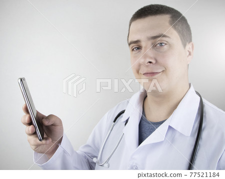 The doctor is holding a smartphone. Medical consultation by phone. Mobile app for healthcare providers The doctor is holding a smartphone. Medical consultation by phone. Mobile app for healthcare providers 77521184