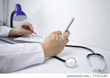 The doctor is holding a smartphone. Medical consultation by phone. Mobile app for healthcare providers 77521186