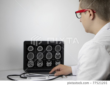 A radiologist doctor examines the result of a computed tomography of the brain on a computer monitor. Diagnosis of neurological and oncological diseases 77521201