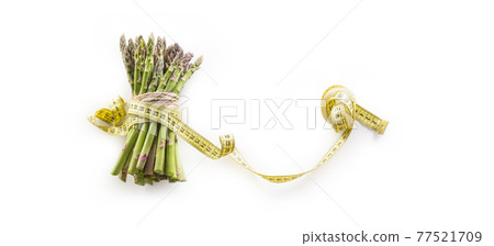 Fresh green asparagus with measure tape isolated on white background Fresh green asparagus with measure tape isolated on white background 77521709