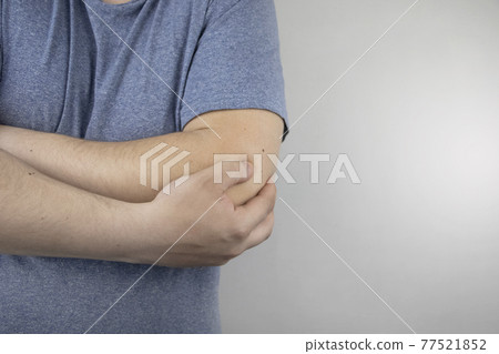 A man suffers from elbow pain. Damaged elbow joint, bone fracture, or sprain. Hand injury and flexion pain concept 77521852