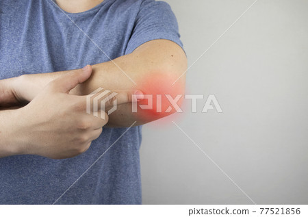 A man suffers from elbow pain. Damaged elbow joint, bone fracture, or sprain. Hand injury and flexion pain concept 77521856