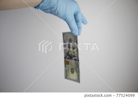 Hand in glove holds dollars with germs. The concept of dirty money as a carrier of bacteria and viruses Hand in glove holds dollars with germs. The concept of dirty money as a carrier of bacteria and viruses 77524099