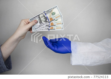 Patient's hand holds out money to the doctor. The concept of corruption in healthcare, bribery or paid medicine 77524113