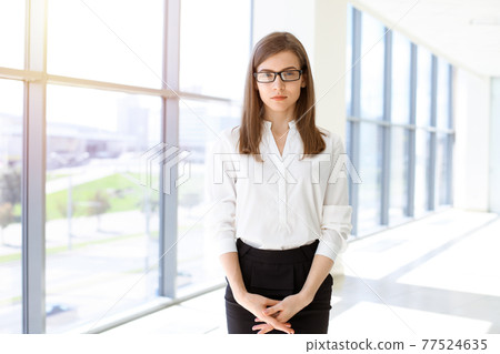 Beautiful female specialist with dark hair standing in sunny office and smiling charmingly. Working on design, data analysis, plan strategy 77524635
