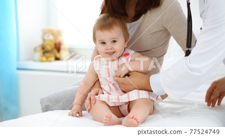 Happy smiling girl-child at usual medical inspection. Doctor and female toddler patient in the clinic. Medicine, healthcare concepts Happy smiling girl-child at usual medical inspection. Doctor and female toddler patient in the clinic. Medicine, healthcare concepts 77524749