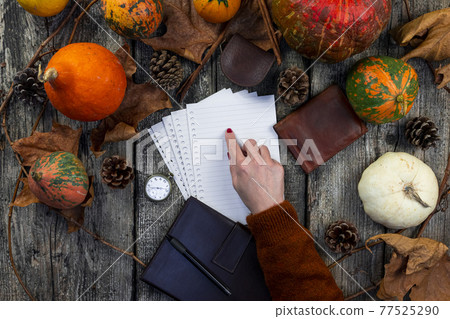 Woman pointing finger at Blank notepad sheet on a rustic wooden table with pumpkins, autumn leaves, pocket watch and leather wallet. Fall and Thanksgiving concept. For Copy space Woman pointing finger at Blank notepad sheet on a rustic wooden table with pumpkins, autumn leaves, pocket watch and leather wallet. Fall and Thanksgiving concept. For Copy space 77525290