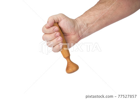 Hand holds a wooden pestle for a mortar on a white background 77527857