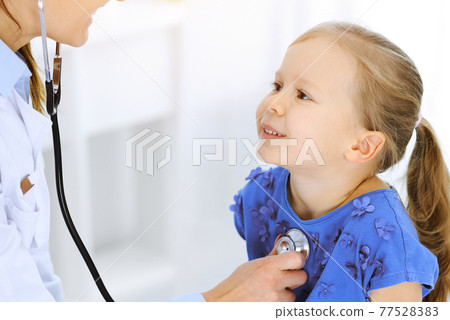 Doctor examining a little girl by stethoscope. Happy smiling child patient at usual medical inspection. Medicine and healthcare concepts Doctor examining a little girl by stethoscope. Happy smiling child patient at usual medical inspection. Medicine and healthcare concepts 77528383