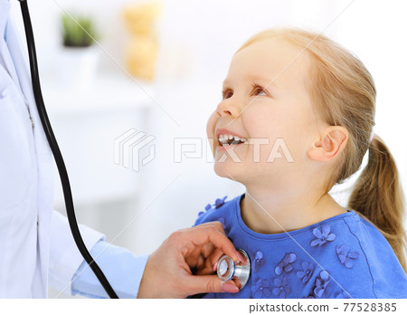 Doctor examining a little girl by stethoscope. Happy smiling child patient at usual medical inspection. Medicine and healthcare concepts 77528385