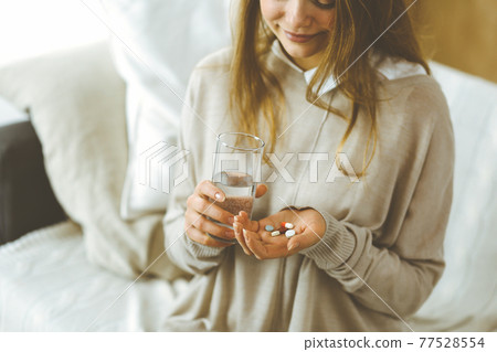 Close-up woman holding pills time to take medications, cure for headache, high blood pressure or cholesterol level remedy pain killer drugs. Stay at home concept during Coronavirus pandemic and self 77528554
