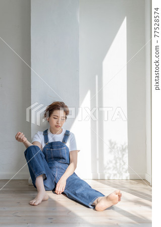 Genderless LGBT boy-like girl wearing overalls and sitting on the floor 77528574