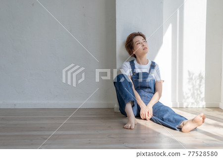 無性別的 LGBT 男孩般的女孩穿著工作服坐在地板上 無性別的 LGBT 男孩般的女孩穿著工作服坐在地板上 77528580