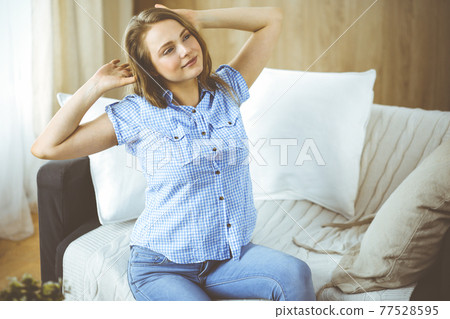 Happy blond woman put hands behind head sitting leaned on couch caucasian female enjoy lazy weekend or vacation in cozy living room, housewife relaxing feels satisfied accomplish chores housework 77528595
