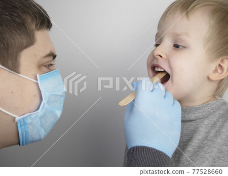 An otolaryngologist examines a child's throat with a wooden spatula. A possible diagnosis is inflammation of the pharynx, tonsils or pharyngitis. The concept of treatment and prevention of childhood An otolaryngologist examines a child's throat with a wooden spatula. A possible diagnosis is inflammation of the pharynx, tonsils or pharyngitis. The concept of treatment and prevention of childhood 77528660
