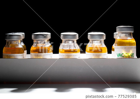 Vials with coronavirus vaccine in packaging on a black background and illuminated by a beam of light. Population vaccination recipe, vaccine research, SARS-Cov-2 Vials with coronavirus vaccine in packaging on a black background and illuminated by a beam of light. Population vaccination recipe, vaccine research, SARS-Cov-2 77529385