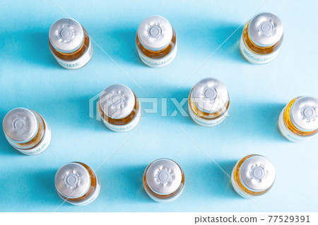 pattern from a vial with a coronavirus vaccine on a blue background. Many vials, vaccine side effects, macro pattern from a vial with a coronavirus vaccine on a blue background. Many vials, vaccine side effects, macro 77529391