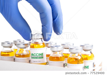 Doctor in medical glove holds in his hand a vial of vaccine for injection for coronavirus COVID-19 cure in research laboratory. Vaccination concept, pandemic. Macro. Doctor in medical glove holds in his hand a vial of vaccine for injection for coronavirus COVID-19 cure in research laboratory. Vaccination concept, pandemic. Macro. 77529400