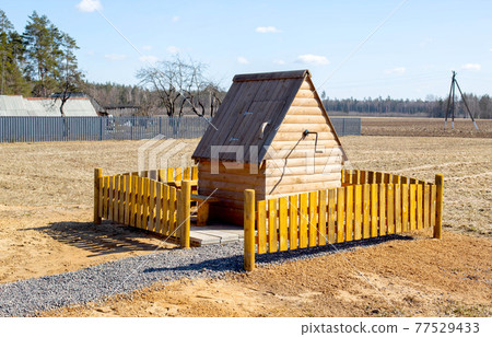 Beautiful and modern wooden well with water in a village in nature, background Beautiful and modern wooden well with water in a village in nature, background 77529433
