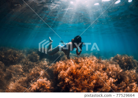 Woman with diving mask posing underwater in transparent ocean with sun rays Woman with diving mask posing underwater in transparent ocean with sun rays 77529664