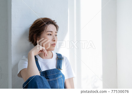 Genderless LGBT boy-like girl sitting in overalls 77530076