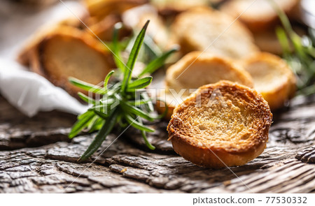 Crunchy and savory bake rolly with goldish color served in the paper with fresh green rosemary 77530332