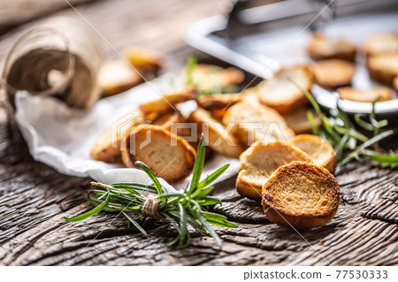 Crispy bake rolls baked on the metal rustic baking pan and served in the paper with rosemary tied by flax twine 77530333
