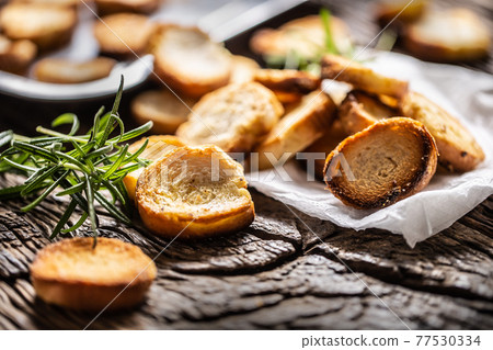 Crunchy and savory bake rolly with goldish color served in the paper with fresh green rosemary Crunchy and savory bake rolly with goldish color served in the paper with fresh green rosemary 77530334