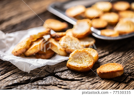 Freshly baked crispy bake rolls with goldish colour served in the paper on a rustic wooden desk Freshly baked crispy bake rolls with goldish colour served in the paper on a rustic wooden desk 77530335