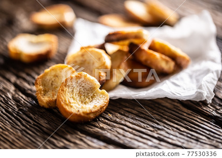 Freshly baked crispy bake rolls with goldish colour served in the paper on a rustic wooden desk Freshly baked crispy bake rolls with goldish colour served in the paper on a rustic wooden desk 77530336