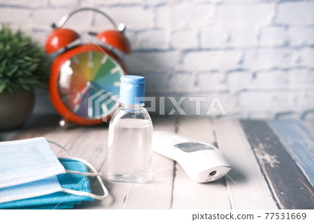 Surgical masks, thermometer and hand sanitizer on orange background Surgical masks, thermometer and hand sanitizer on orange background 77531669