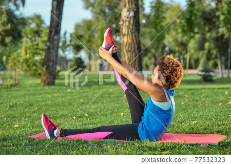 Sporty Afro American girl doing exercise in park 77532323