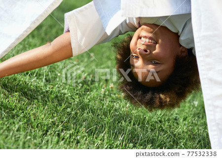 Cheerful Afro American girl doing exercise outdoors Cheerful Afro American girl doing exercise outdoors 77532338