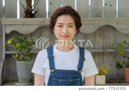 Genderless LGBT boy-like girl young woman standing in the garden Genderless LGBT boy-like girl young woman standing in the garden 77532535