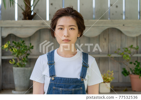 站在花園裡的無性別 LGBT 男孩般的女孩年輕女人 77532536