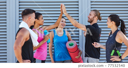 Happy mixed race youth giving high five near wall on street Happy mixed race youth giving high five near wall on street 77532540