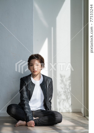 無性別的 LGBT 男孩般的女孩,穿著皮夾克的年輕女子坐在地板上 無性別的 LGBT 男孩般的女孩,穿著皮夾克的年輕女子坐在地板上 77533244