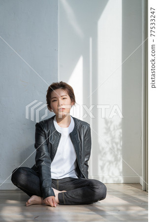 無性別的 LGBT 男孩般的女孩,穿著皮夾克的年輕女子坐在地板上 無性別的 LGBT 男孩般的女孩,穿著皮夾克的年輕女子坐在地板上 77533247