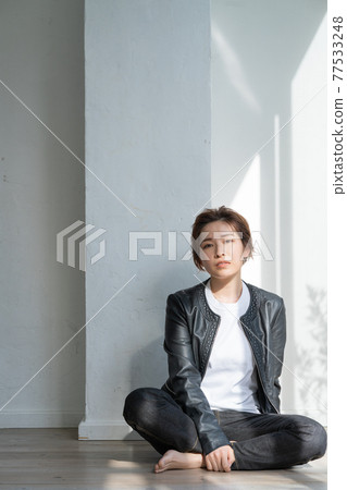 無性別的 LGBT 男孩般的女孩，穿著皮夾克的年輕女子坐在地板上 77533248