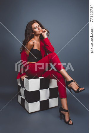 Fashion model in red suit, beautiful young woman. Studio shot. Blue background. Fashion model in red suit, beautiful young woman. Studio shot. Blue background. 77533784