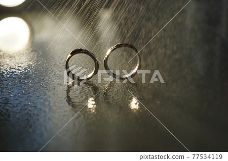 two wedding gold rings reflected in the mirrored surface under the water drops two wedding gold rings reflected in the mirrored surface under the water drops 77534119